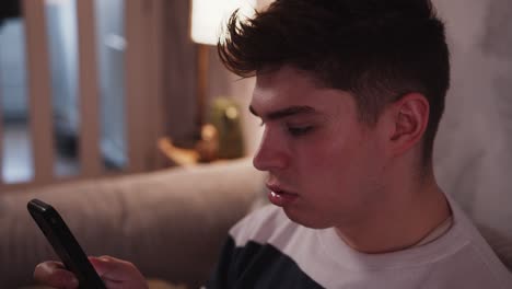 un joven blanco se siente aburrido mientras se desplaza por las redes sociales en su teléfono