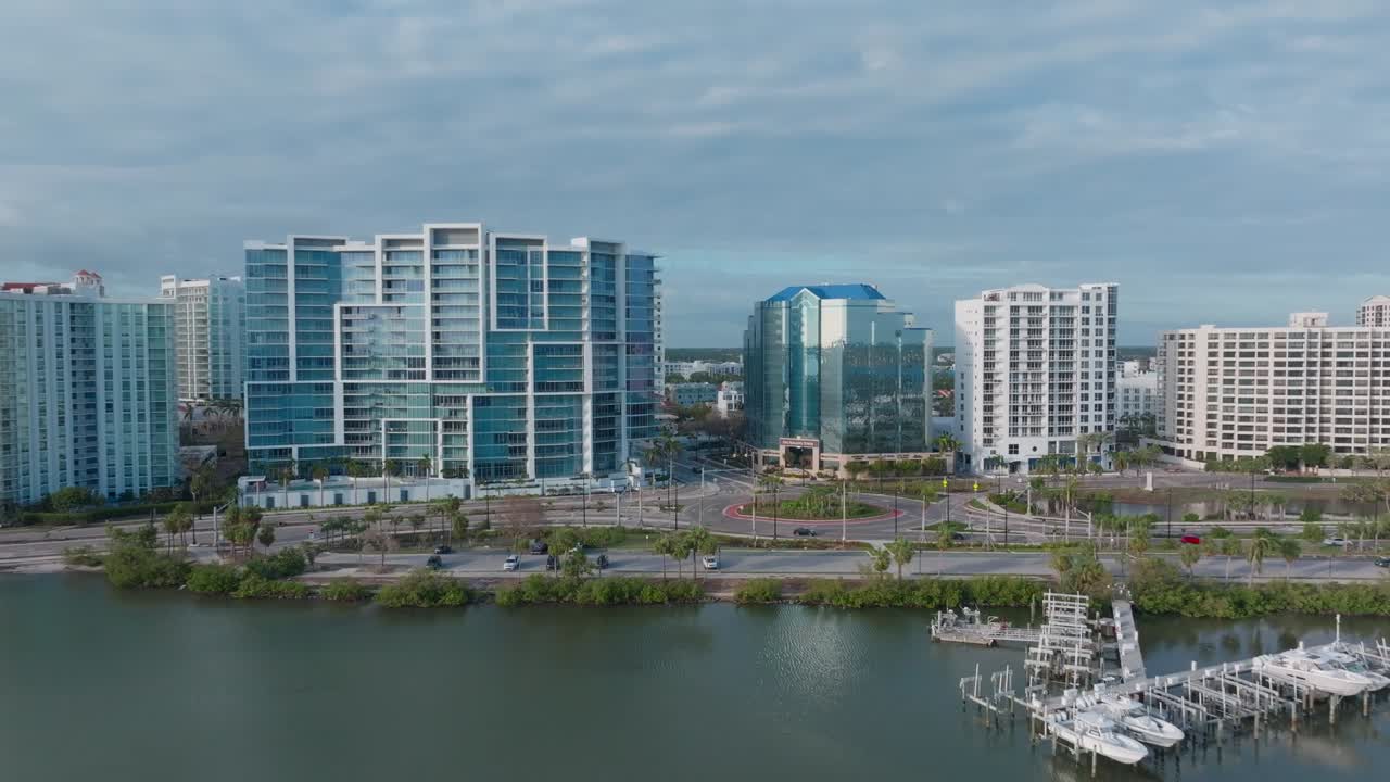 Aerial forward dolly over Marina Jack toward downtown Sarasota roundabout, with overcast skies. Filmed day after Hurricane Milton, showing dock and boats