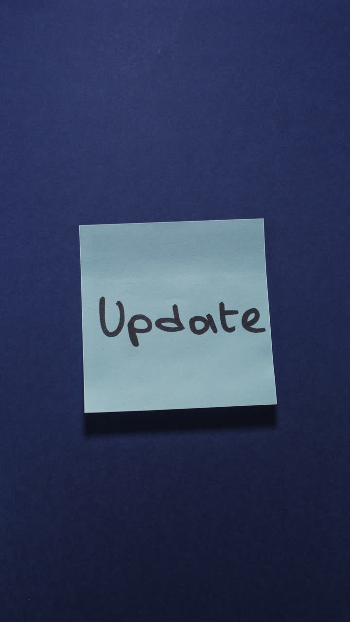 Hands posting Update sticky note on dark blue wall, presenting new information