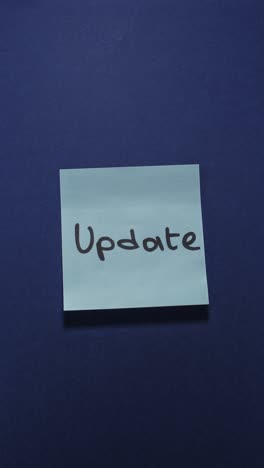 hands posting update sticky note on dark blue wall, presenting new information