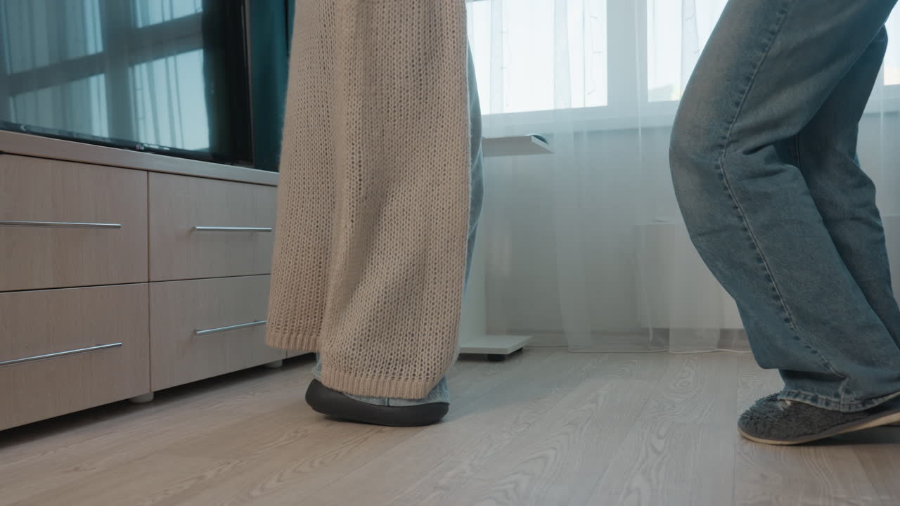 FloorLevel CloseUp Feet Of Parent And Teen In Living Room, Tense Stillness After Argument Near Couch, Denim And Slippers Visible, Family Distance And Tentative Reconciliation Implied