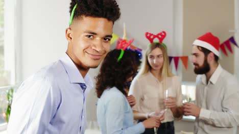 jóvenes trabajadores de oficina hablando y sosteniendo copas con vino espumoso durante la fiesta de navidad en la oficina mientras sus africanos