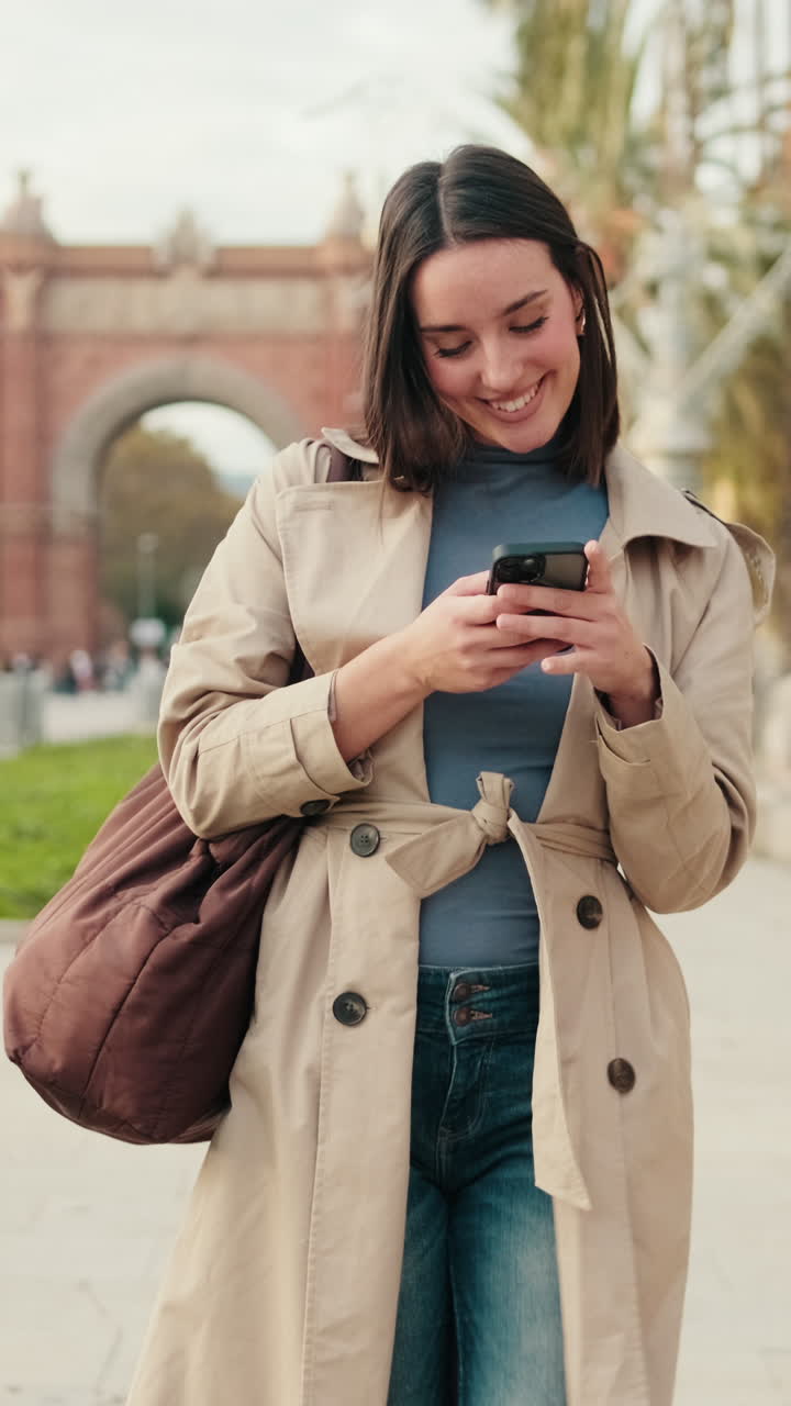 Giovane donna felice che sorride e usa lo smartphone all'aperto in città