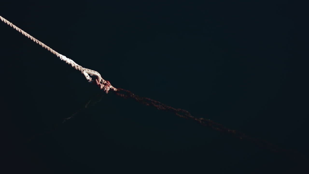 Close up of an aged rope tied to the dock, floating on dark blue sea