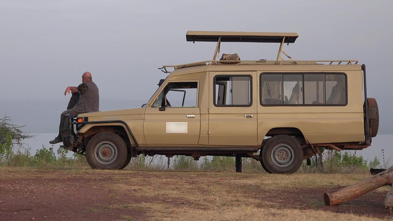 Mies istumassa safariajoneuvossa ja katselemassa järvelle.