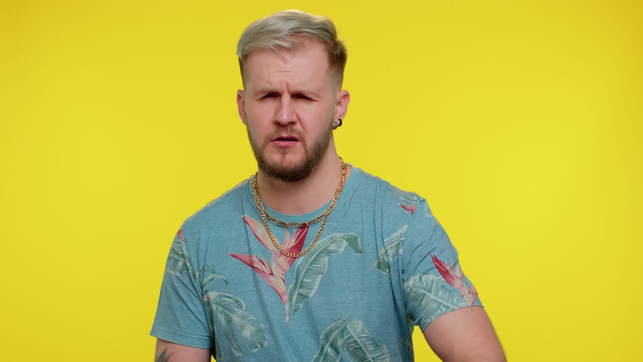 Man with blond hair wearing floral shirt and gold chain looking skeptical