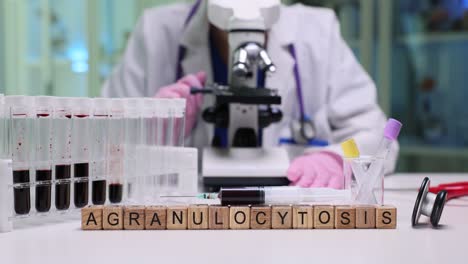 medical laboratory scene with "agranulocytosis" spelled out, blood samples, and a person using a microscope