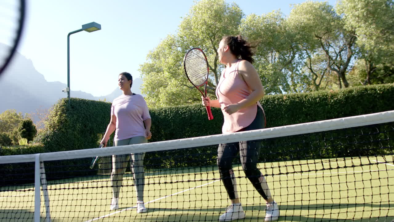 Playing tennis, two women enjoying outdoor activity on sunny day
