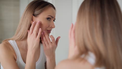 Young-caucasian-woman-in-the-bathroom-having-problems-with-face-skin.