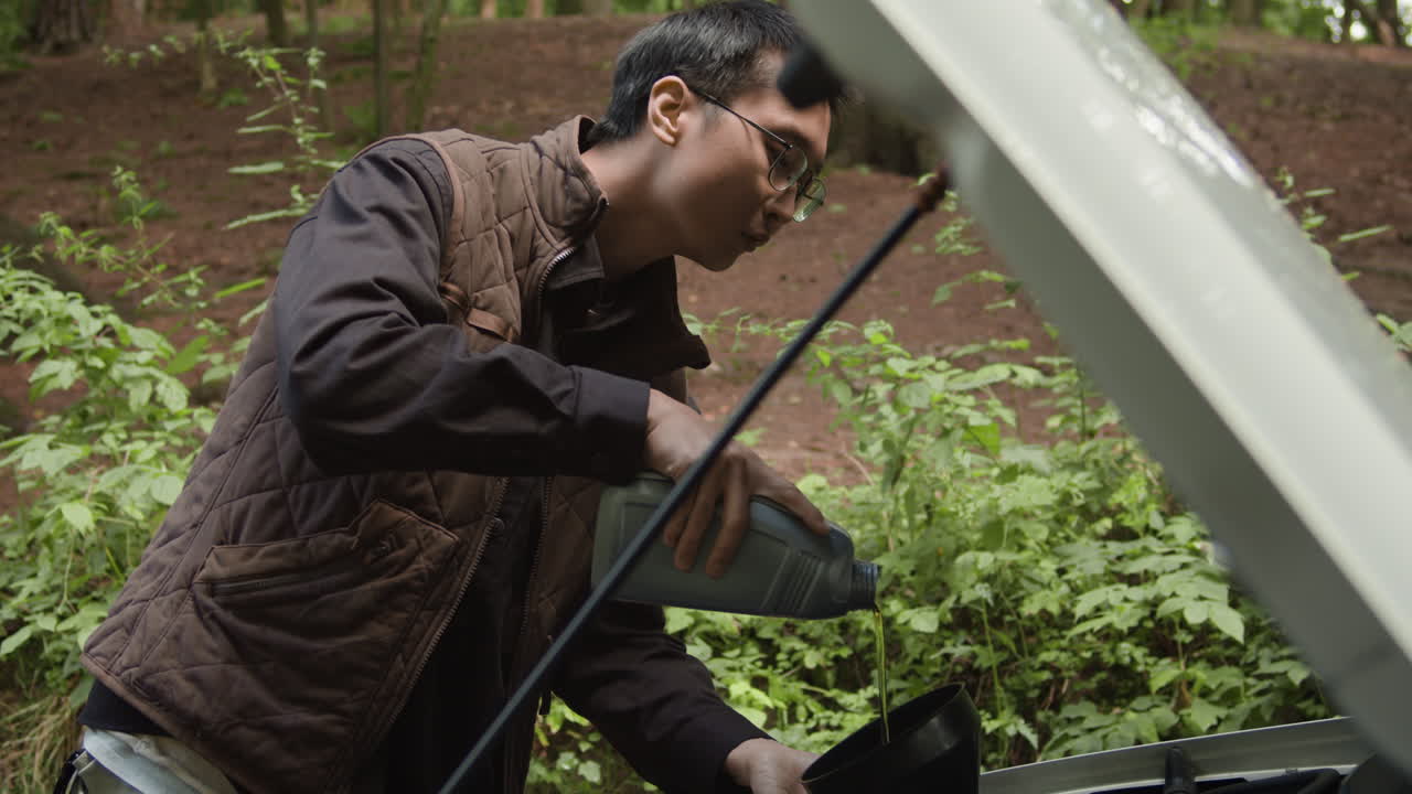 Man performs car maintenance in the forest