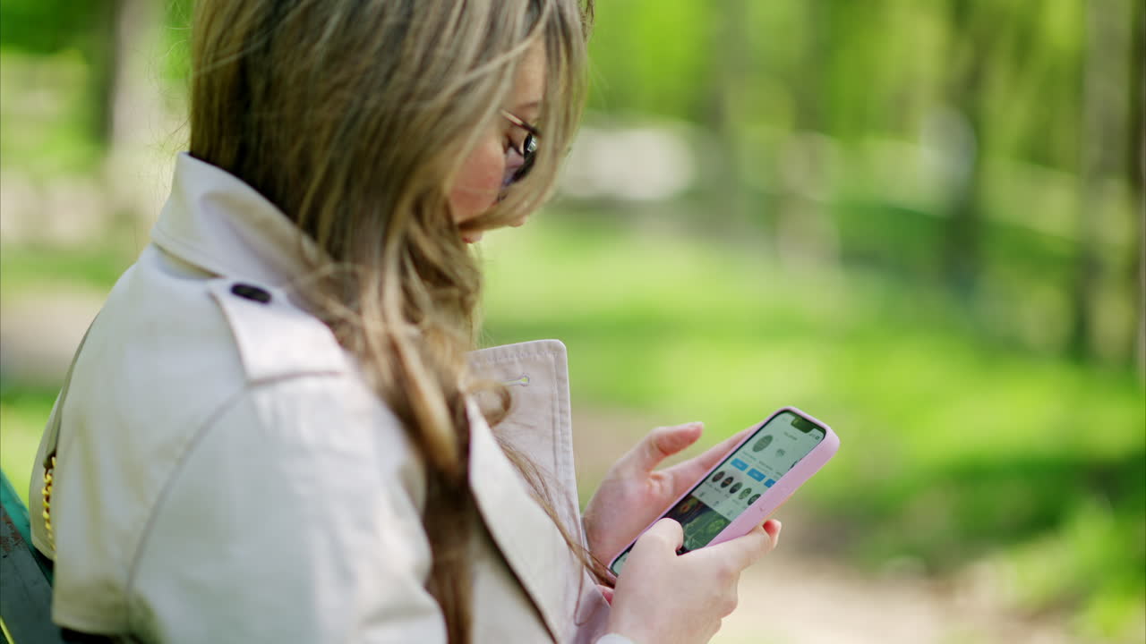 Woman scrolling through her phone on a bench in the park
