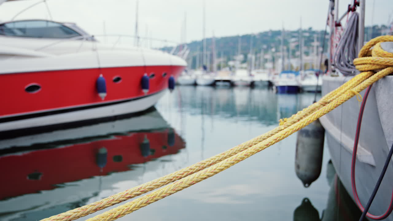 Modern red and white yacht docked in calm marina waters with clear reflections