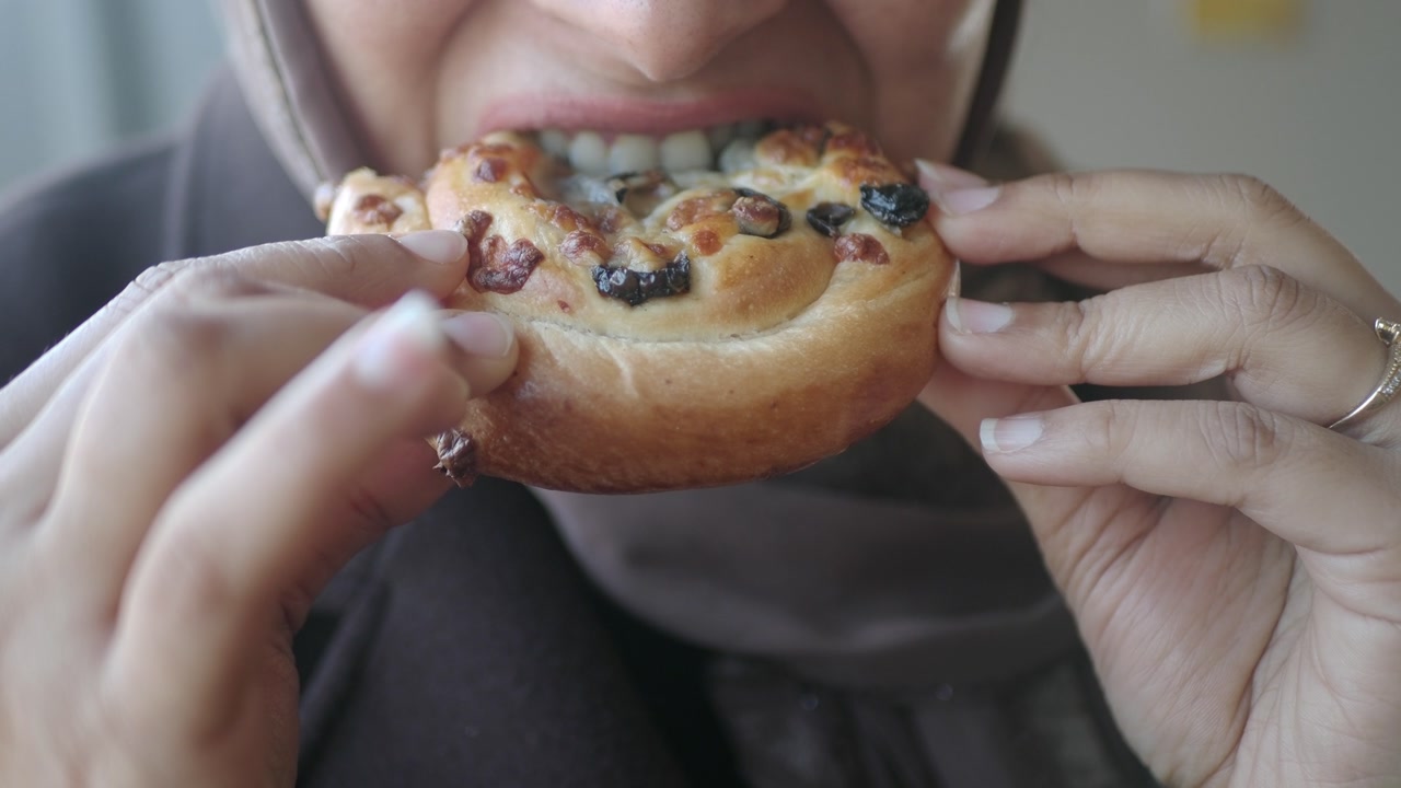 Close-up of a Person Eating a Sweet Pastry with Raisins
