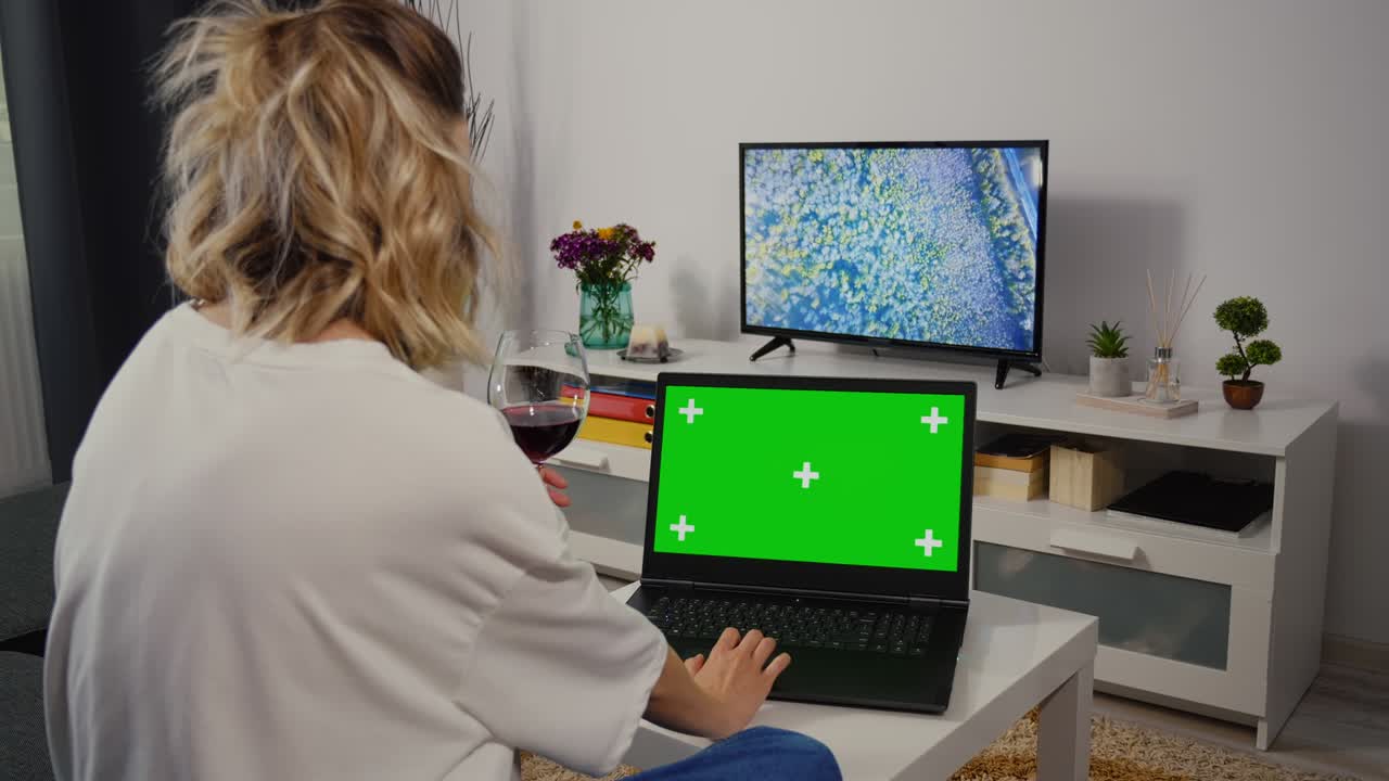 mujer sentada en el sofá usando una computadora portátil con pantalla verde y llave de croma.