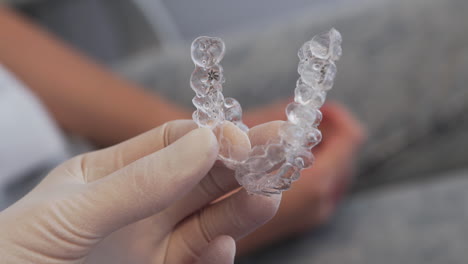 close up - dentist holding transparent invisalign aligner