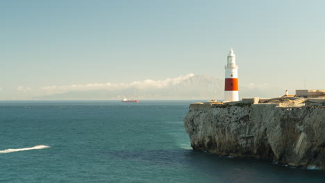 Estepona-lighthouse-and-moving-small-boats-and-cargo-ships,-time-lapse