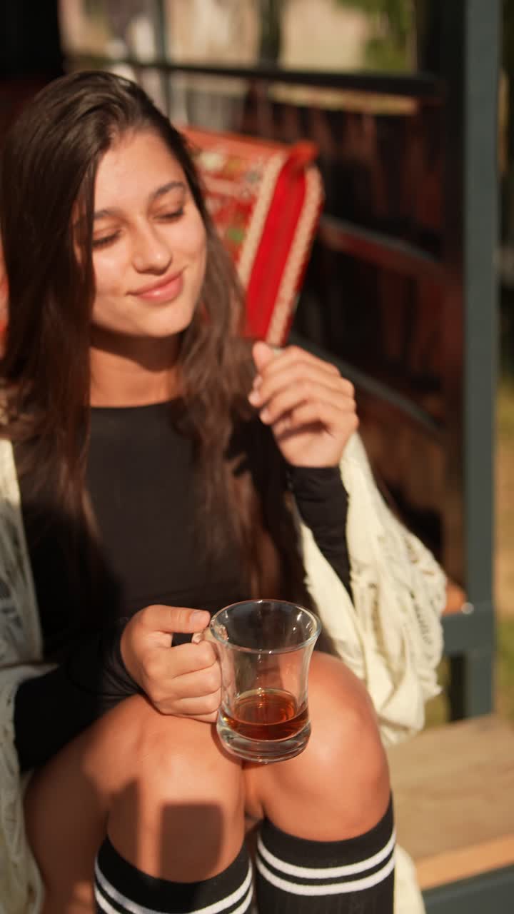 Giovane donna che gusta un tè all'aperto