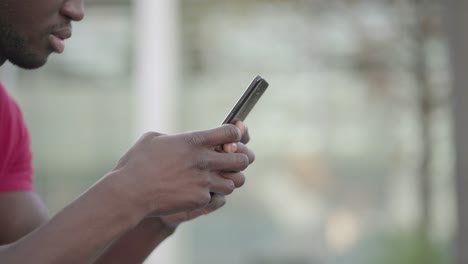 Primer-Plano-De-Manos-De-Hombres-Jóvenes-Escribiendo-En-Un-Teléfono-Inteligente-En-El-Parque