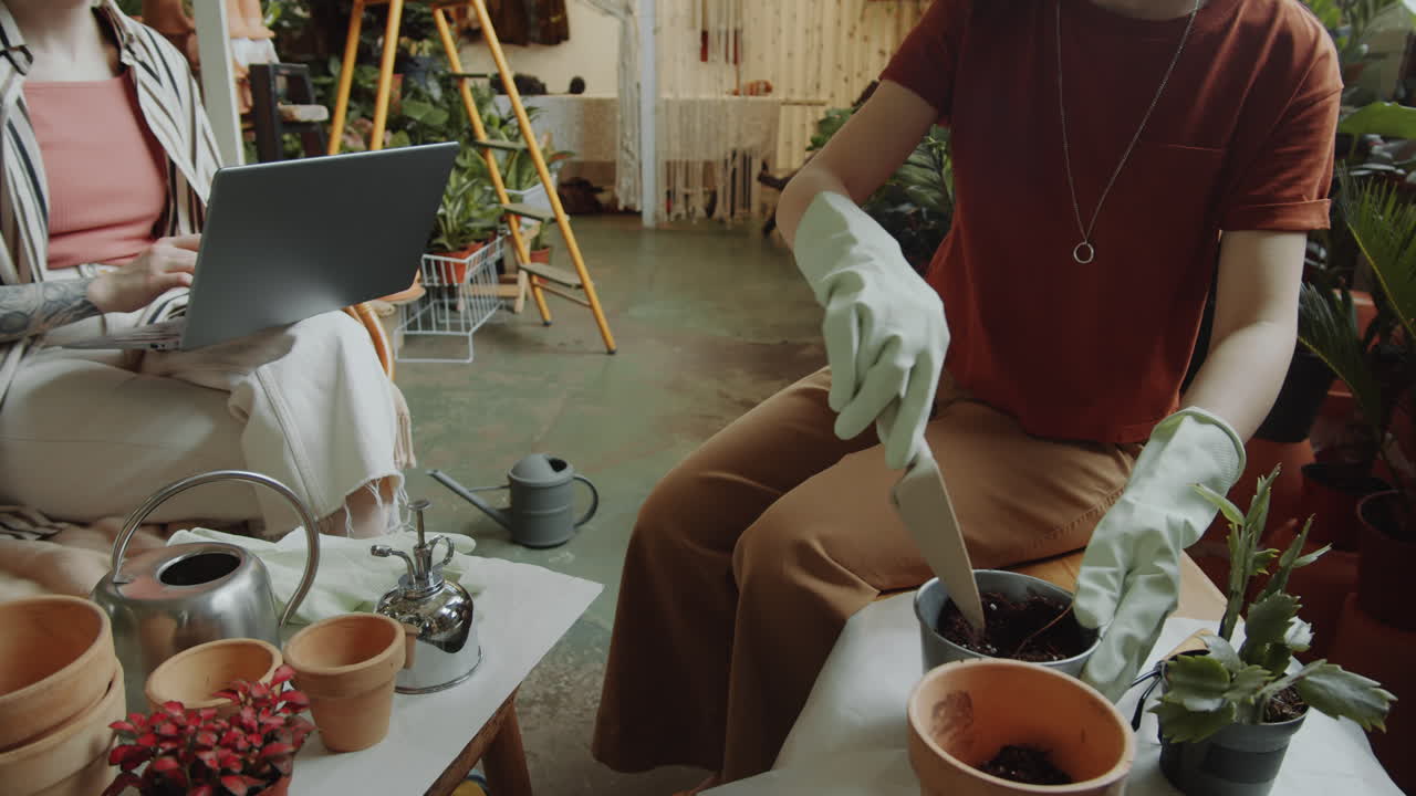 chica llenando la olla con tierra y hablando con un compañero de trabajo en la tienda de flores