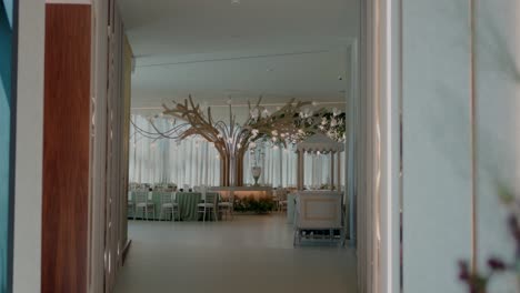 view of a beautifully decorated wedding reception hall with tree-like decor and elegant seating arrangements