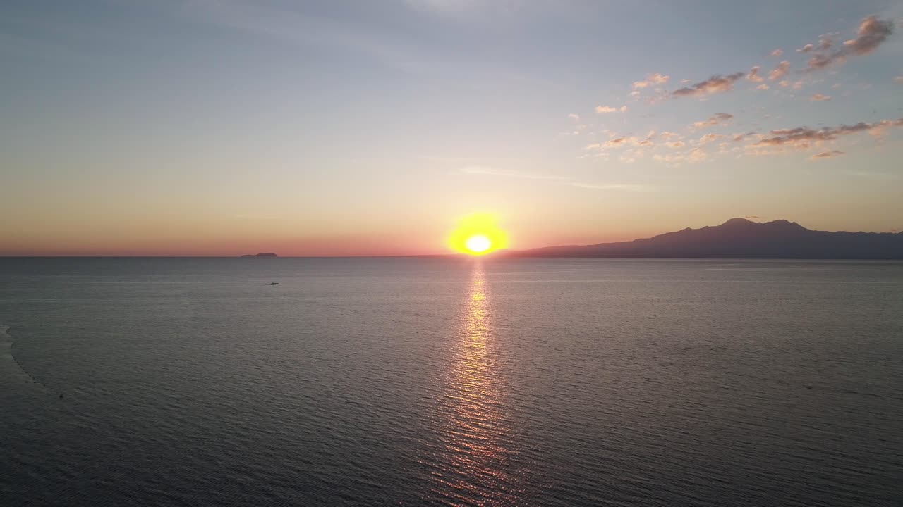 Beautiful sunset above Philippines sea with silhouette of distant island, aerial