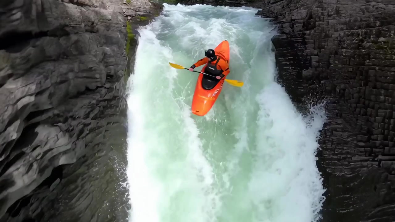 Kayaker che pagaia su una cascata in un canyon roccioso