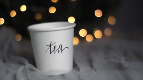 Christmas-tea-paper-cup-drink-on-a-cozy-netted-bed,-handheld-shot