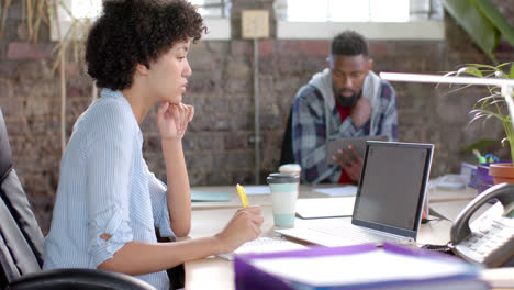 Focused diverse colleagues using tablet and laptop with copy space in office in slow motion