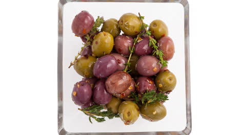 animación de aceitunas con hierba en un plato sobre fondo blanco