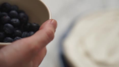 closeup of crop cook decorating cake with blueberries