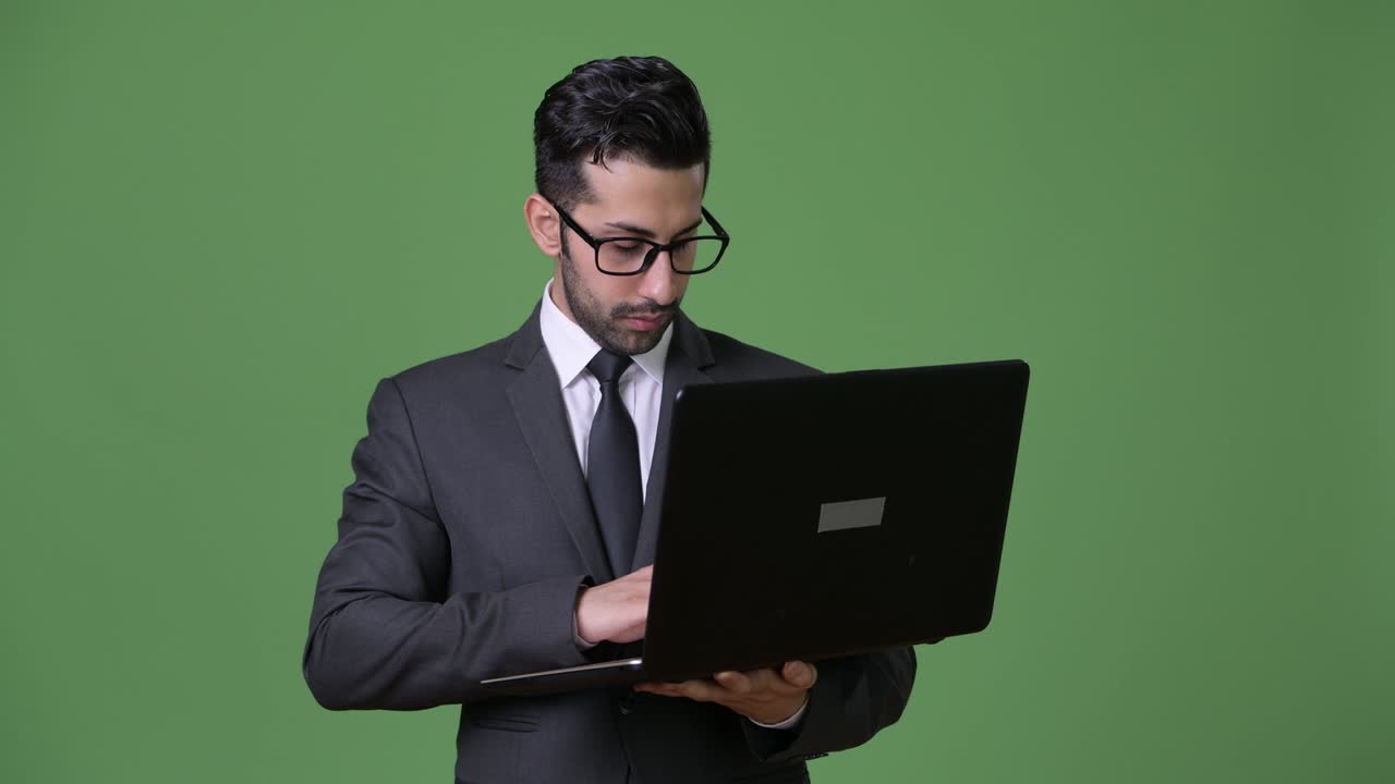 joven empresario persa barbudo y guapo contra un fondo verde