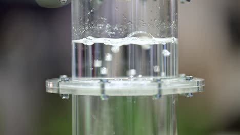 hydrogen gas is bubbeling through a membrane in a plastic cylinder filled with water, close up