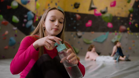 chica adolescente bebiendo agua en un gimnasio de escalada