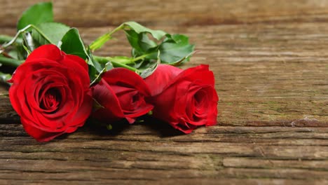 three red roses on wooden surface 4k