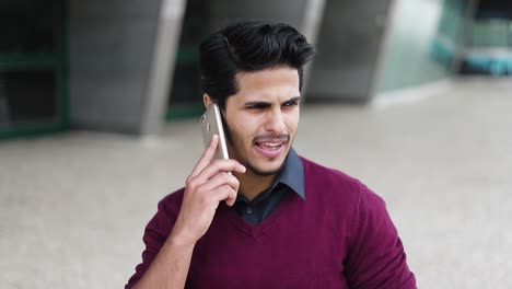 Handsome-young-man-talking-on-phone-outside,-looking-serious