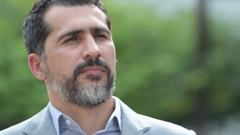 persa guapo hombre de negocios barbudo sonriendo mientras piensa en las calles al aire libre