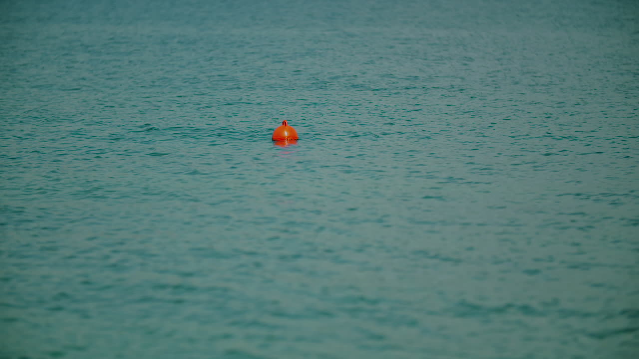 Orange Buoy Floating Calmly on Turquoise Ocean Water