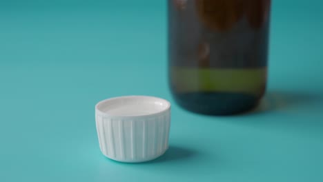 a small ceramic cup of sake with a bottle in the background