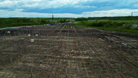 Aerial-flyover-poles-at-a-solar-power-park-construction-site,-sunny,-summer-day