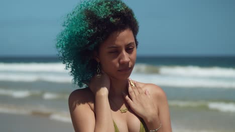 hermosa chica facial de cerca en una playa con cabello rizado verde soplando en el viento