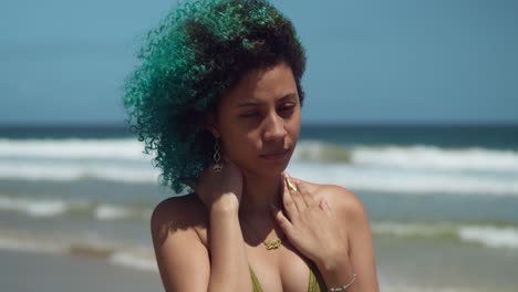 pretty girl facial close up on a beach with green curly hair blowing in the wind