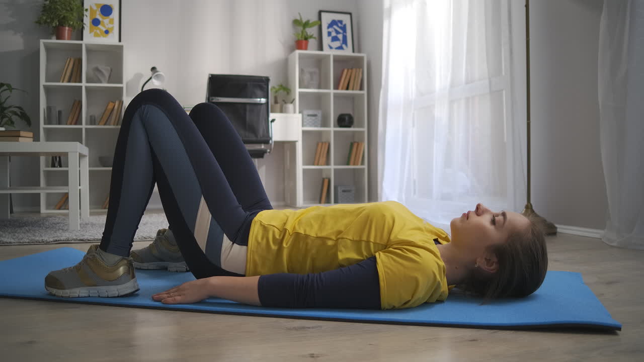 joven está entrenando los músculos de las piernas y las caderas entrenamiento en el hogar fitness y estilo de vida saludable acostado en el suelo de la sala de estar en el apartamento