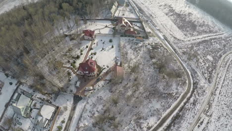 Escena-De-Campo-Invernal-Con-Casas,-Bosques-Y-Campos-Nevados-Vista-Aérea