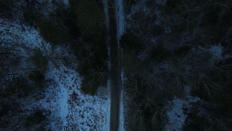 smooth nighttime drone footage of a beautiful road through a snowy winter forest in the appalachian mountains during winter in new york's hudson valley in the catskill mountains sub-range