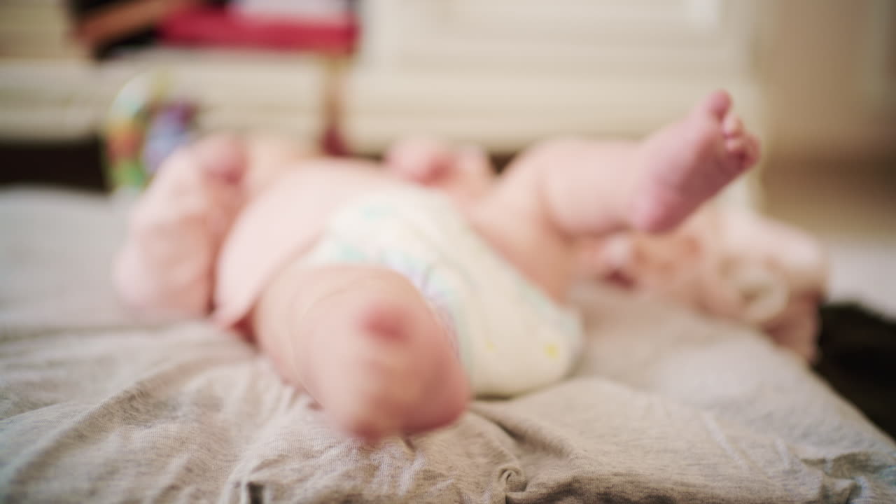 Close up of a newborn baby's feet gently moving while lying on a soft bed