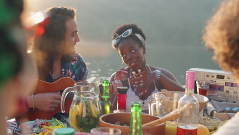 young man and woman playing ukulele and singing at lake party