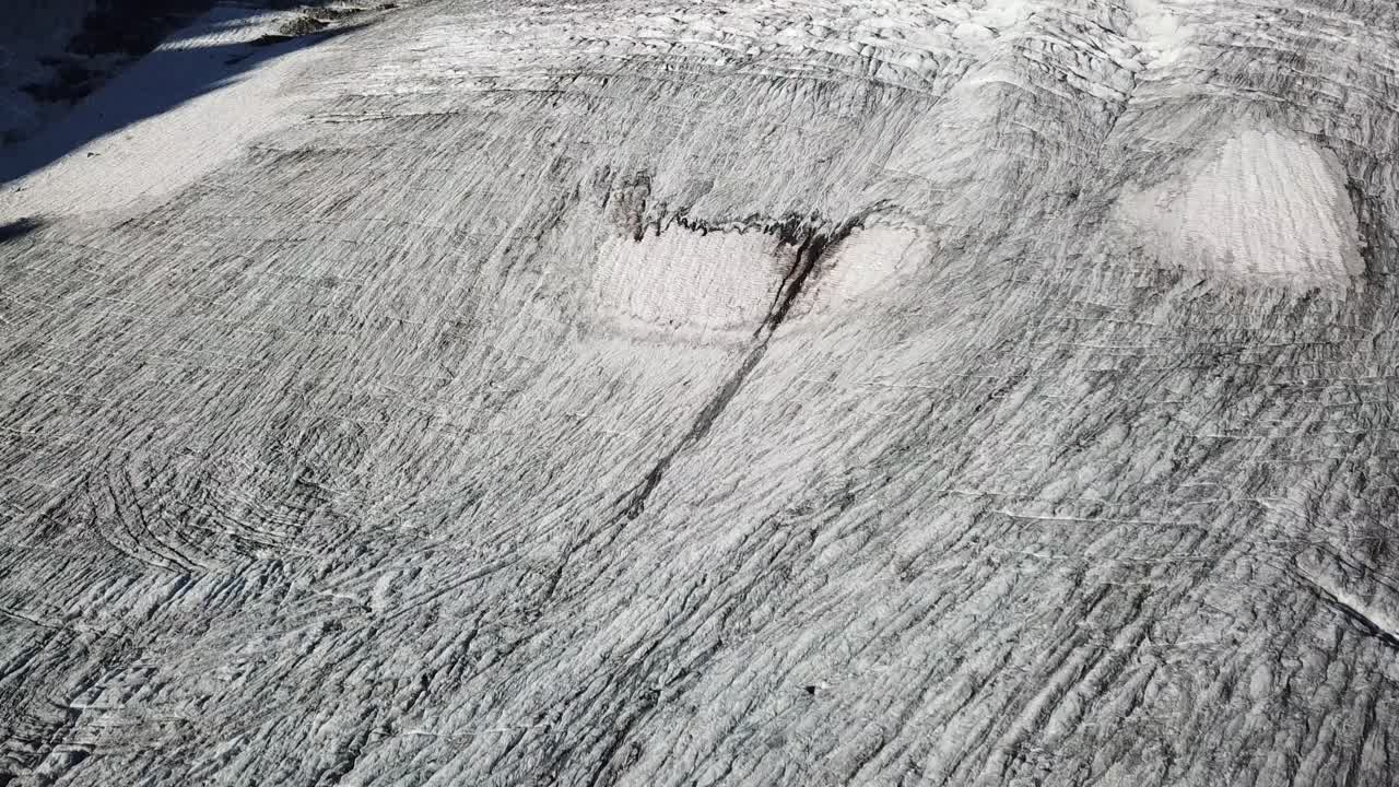 Drone view, tilt up, a glacier with dark crevices in the middle of high mountains, Cabane d'Orny