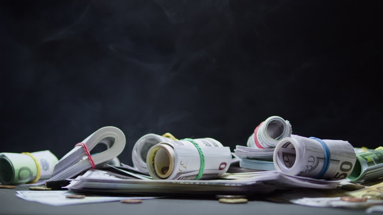 Rolled Cash Bills and Coins with Smoke on Dark Background