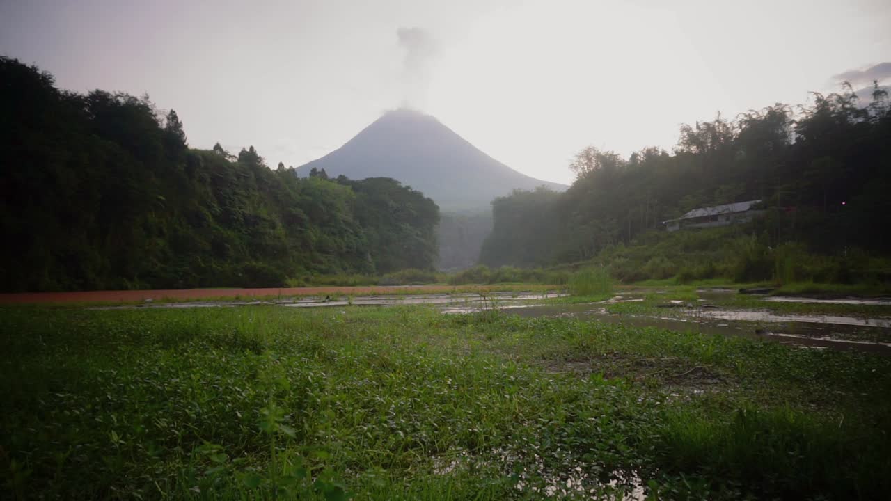 río de montaña cubierto de hierba verde con volcán que emite humo - hermosas imágenes de la naturaleza en la jungla