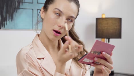 portrait of a happy cute woman applying cosmetics in pink pajamas in the bedroom and dancing